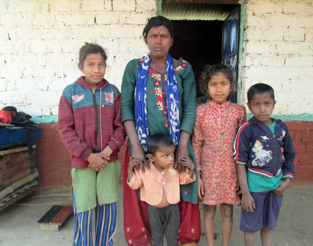 Nepalilainen Janaki Lawad seisoo kotitalonsa edustalla neljän lapsensa kanssa.