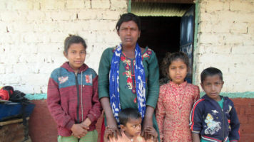 Nepalilainen Janaki Lawad seisoo kotitalonsa edustalla neljän lapsensa kanssa.