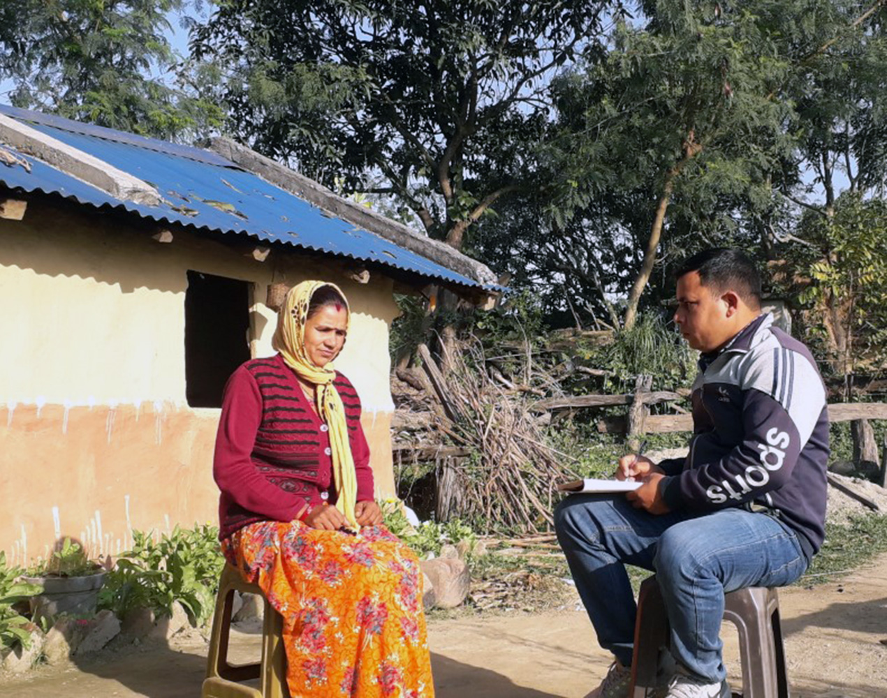 Freed Haliya woman Tulacchi Chaudhary sits in front of her home, being interviewed.