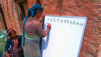 Nepalilainen nainen kirjoittaa valkoiselle taululle