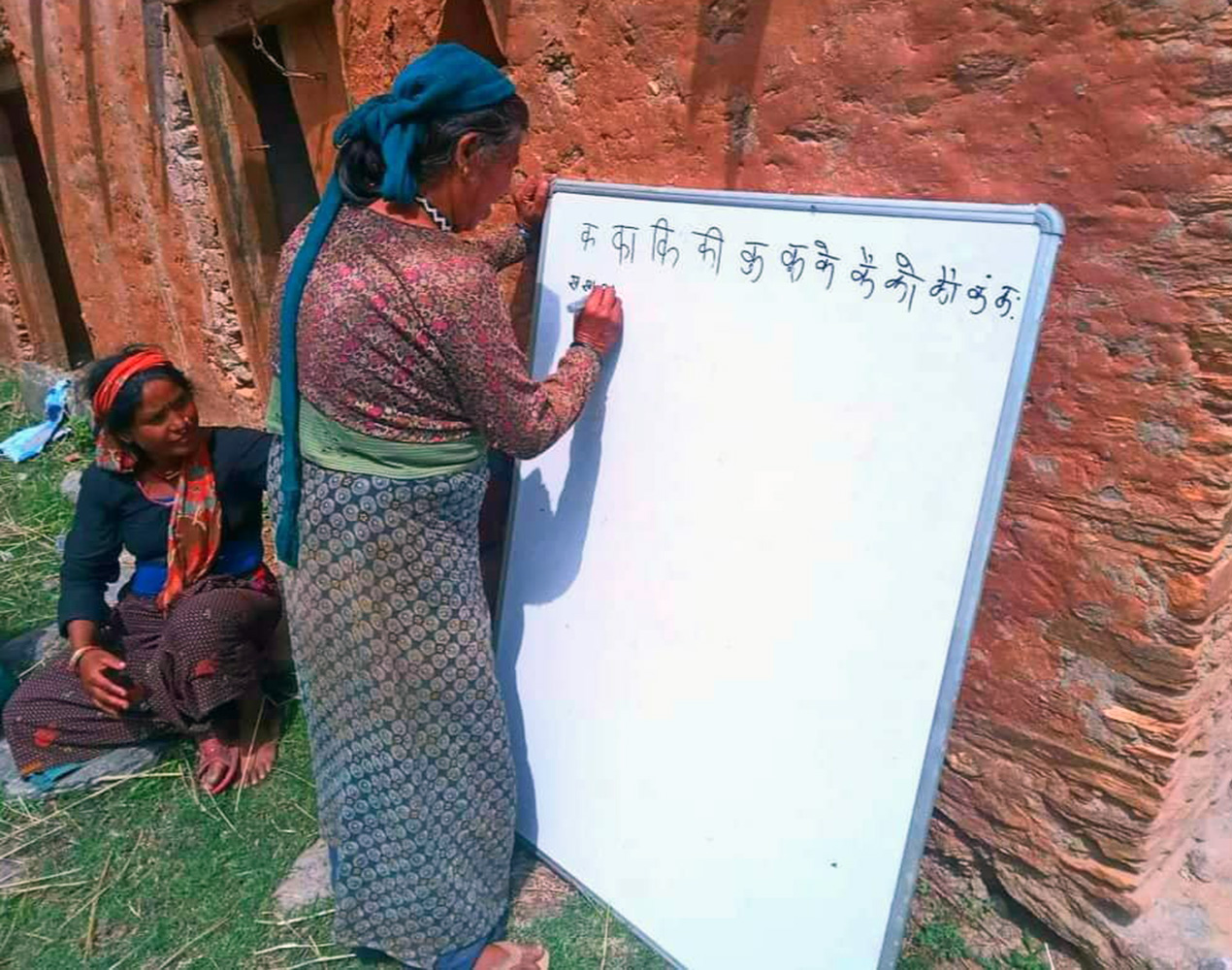 Nepalilainen nainen kirjoittaa valkoiselle taululle