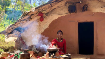 Haliya woman in front of her temporary house, cooking.