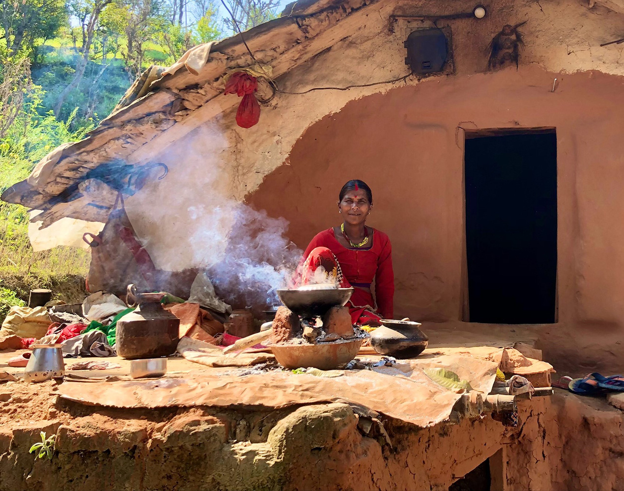 Haliya woman in front of her temporary house, cooking.